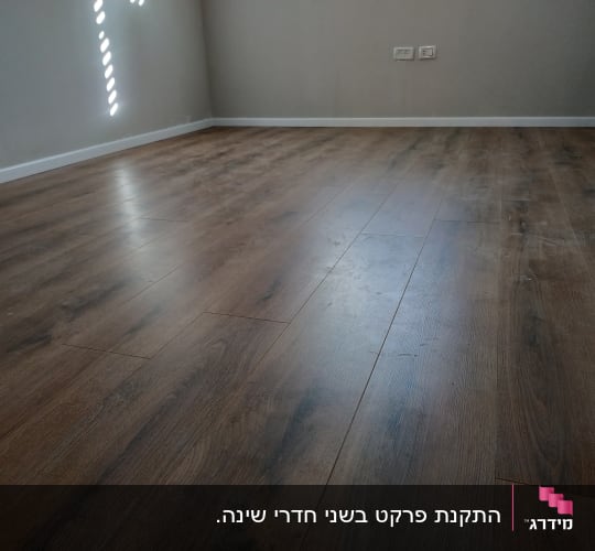 רצפת פרקט עץ כהה בחדר ריק עם קירות בהירים
